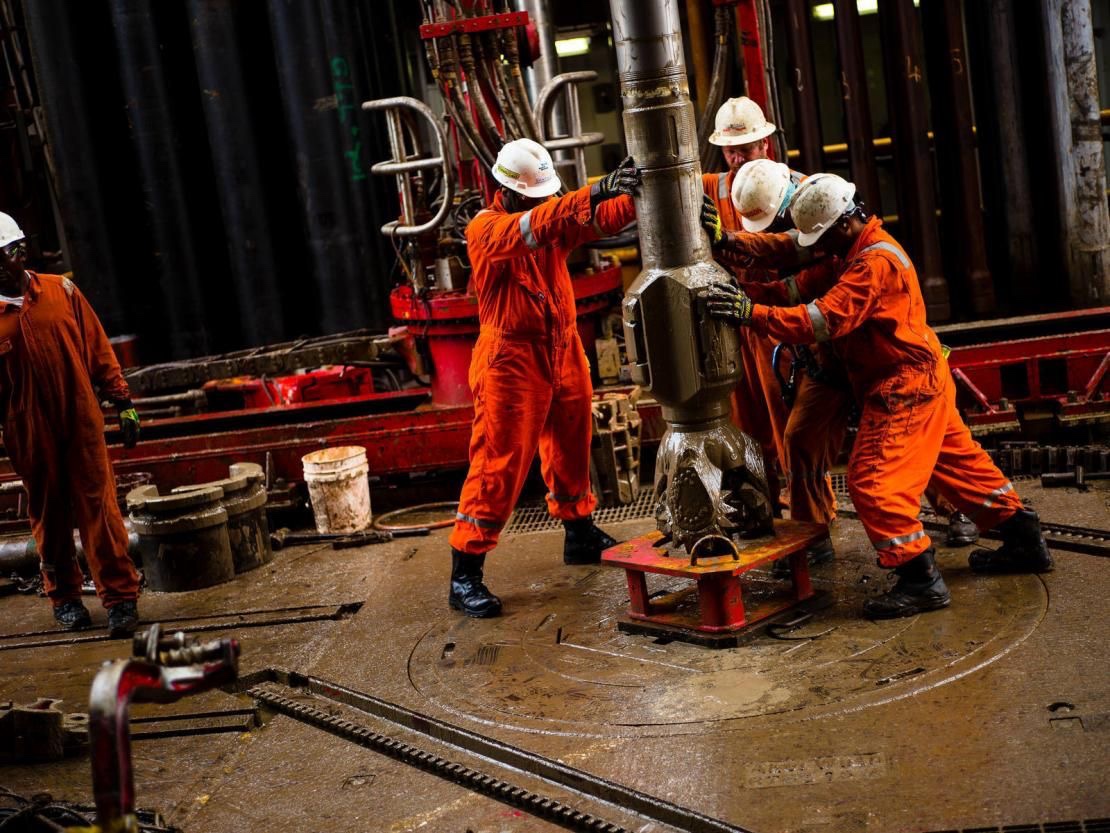 Crew handling drilling equipment on a rig floor